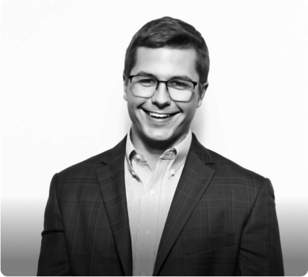Professional headshot of smiling man in glasses and business attire